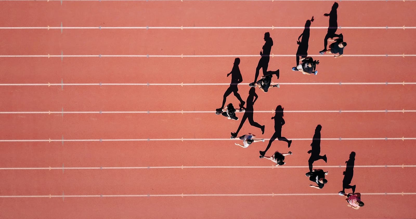 Corredores y sus sombras vistos desde arriba en una pista